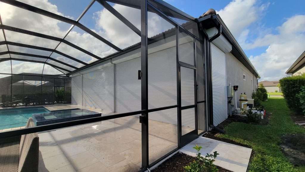 A Screened in Patio With a Swimming Pool in the Background — Naples, FL — Wind Safe Shutters LLC