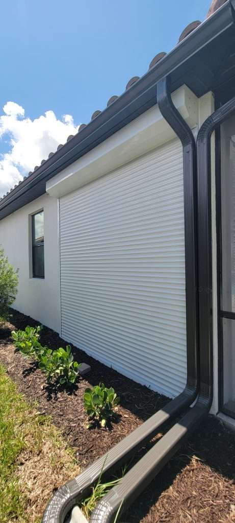 A White House With a Black Gutter and a Screened in Porch — Naples, FL — Wind Safe Shutters LLC