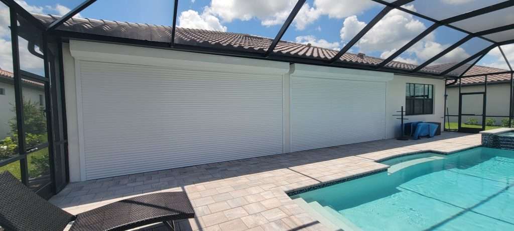 There Is a Swimming Pool in the Backyard of a House — Naples, FL — Wind Safe Shutters LLC