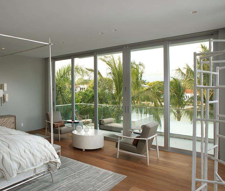 A Bedroom With a Canopy Bed, Chairs, Coffee Table and Sliding Glass Doors — Naples, FL — Wind Safe Shutters LLC