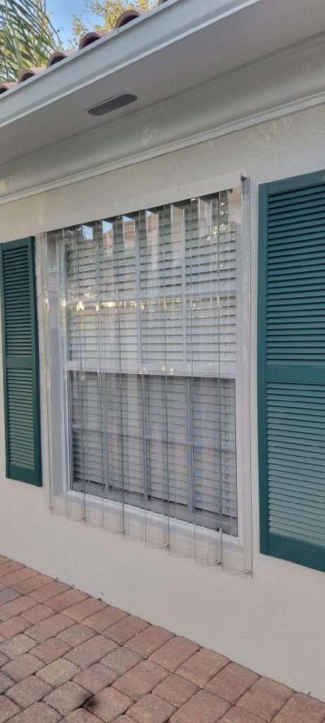 A White House With Green Shutters and a Window — Naples, FL — Wind Safe Shutters LLC