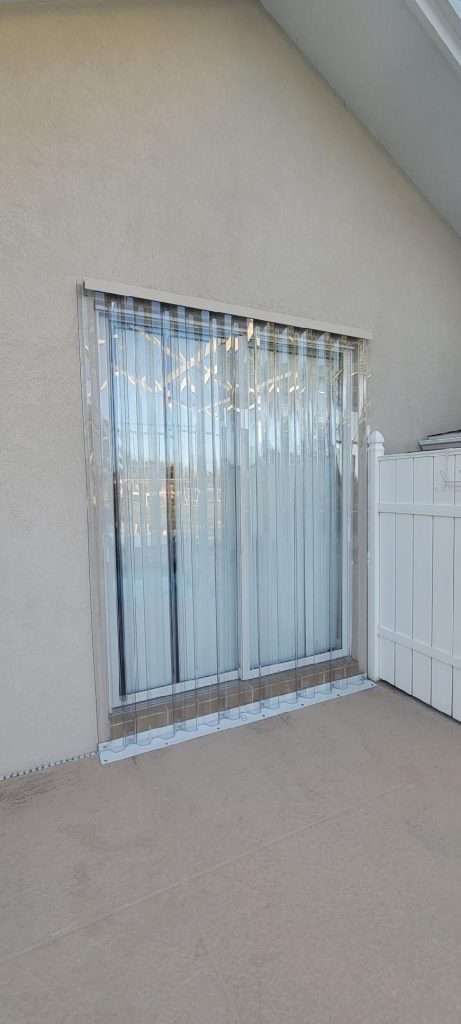 A Patio With a Sliding Glass Door and a White Fence — Naples, FL — Wind Safe Shutters LLC
