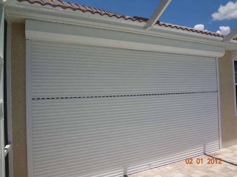 A White Roller Shutter on the Side of a Building — Naples, FL — Wind Safe Shutters LLC