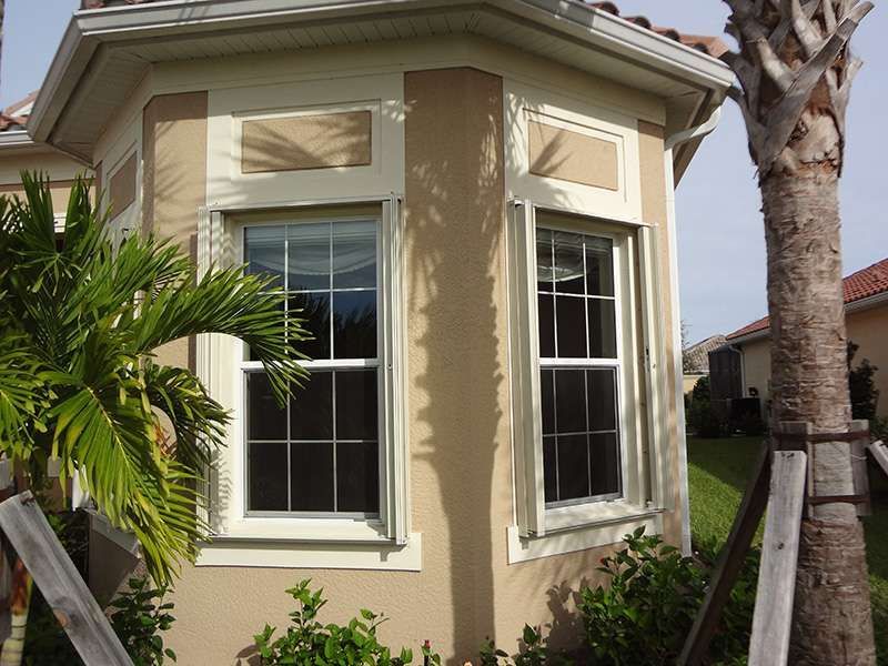 A House With a Palm Tree in Front of It — Naples, FL — Wind Safe Shutters LLC