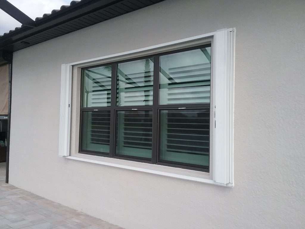 A Large Window With Shutters on the Side of a House — Naples, FL — Wind Safe Shutters LLC