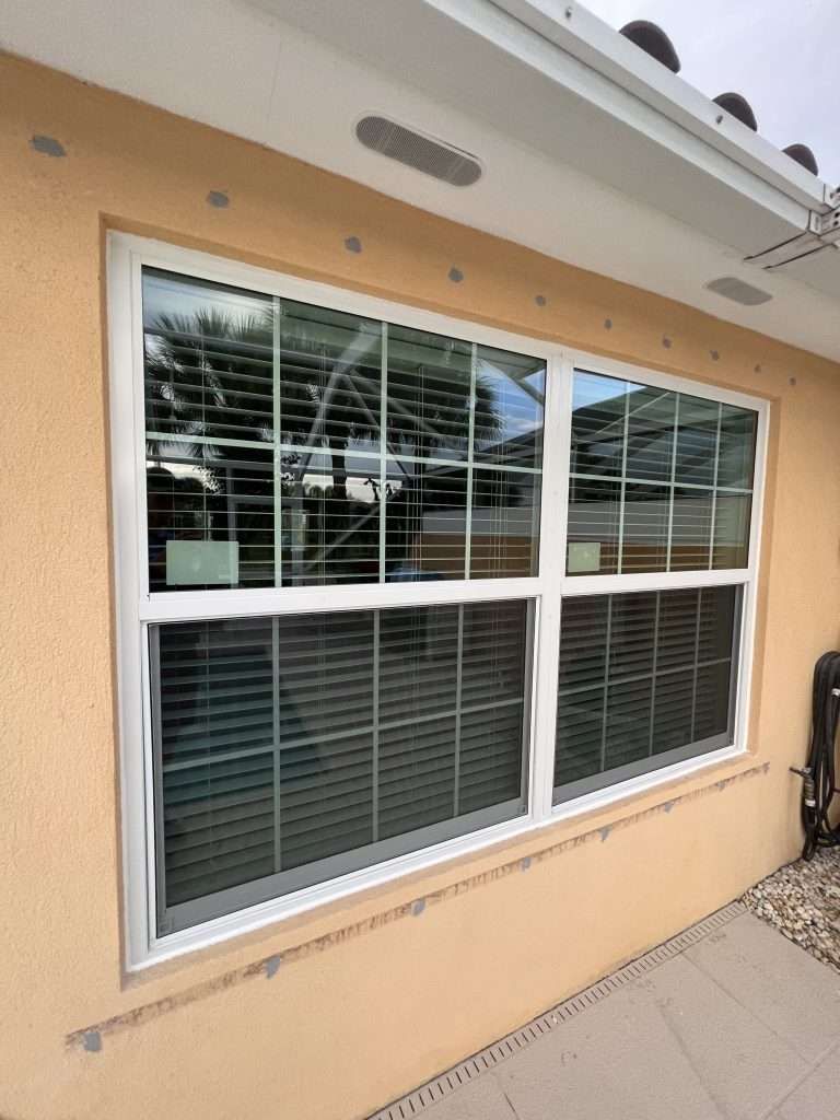 A Large Window on the Side of a House With Blinds — Naples, FL — Wind Safe Shutters LLC
