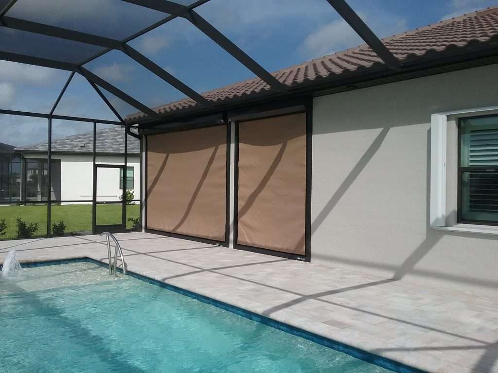 A House With a Screened in Swimming Pool in Front of It — Naples, FL — Wind Safe Shutters LLC