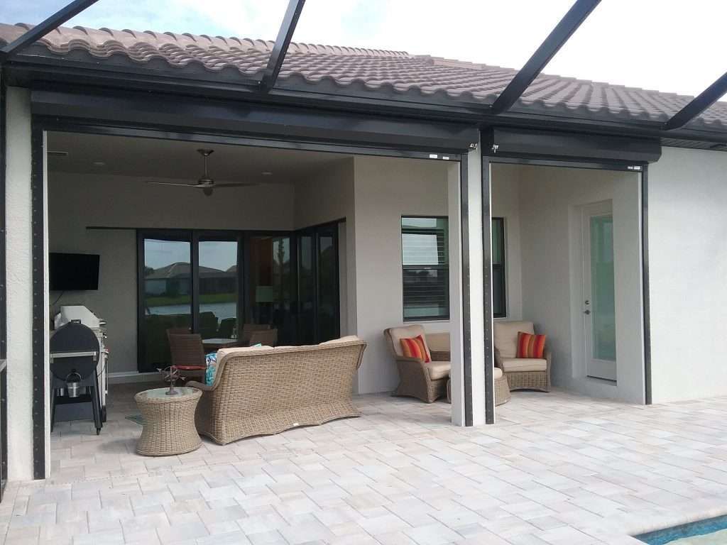 A Patio With Wicker Furniture and a Sliding Glass Door — Naples, FL — Wind Safe Shutters LLC