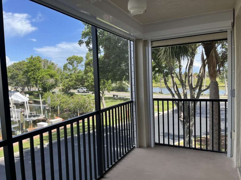 A Screened in Porch With a View of a Lake and Trees — Naples, FL — Wind Safe Shutters LLC