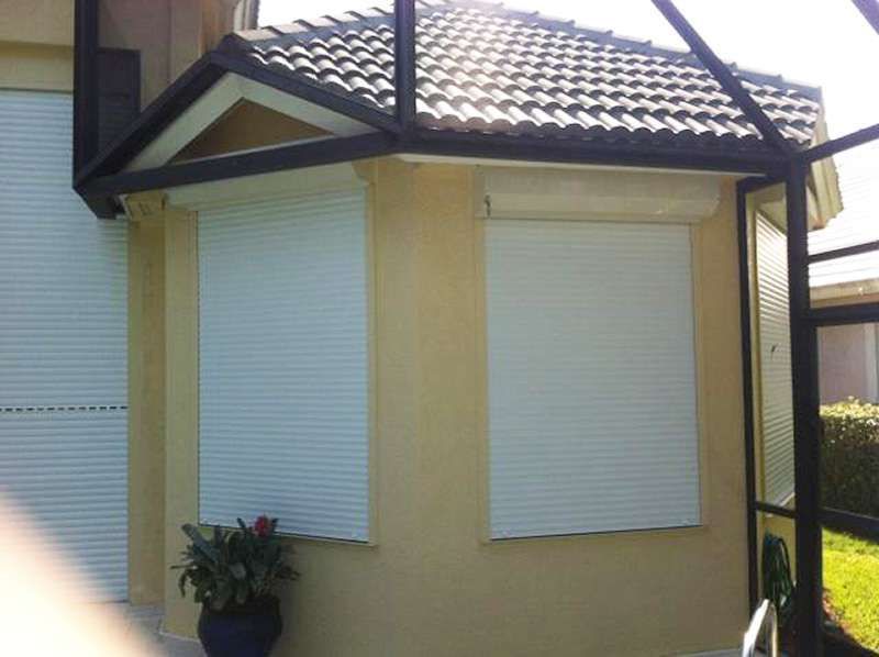 A House With a Black Roof and White Shutters on the Windows — Naples, FL — Wind Safe Shutters LLC