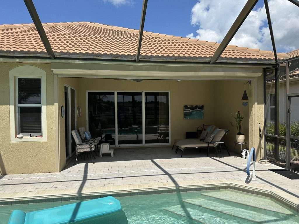 There Is a Swimming Pool in the Backyard of a House — Naples, FL — Wind Safe Shutters LLC