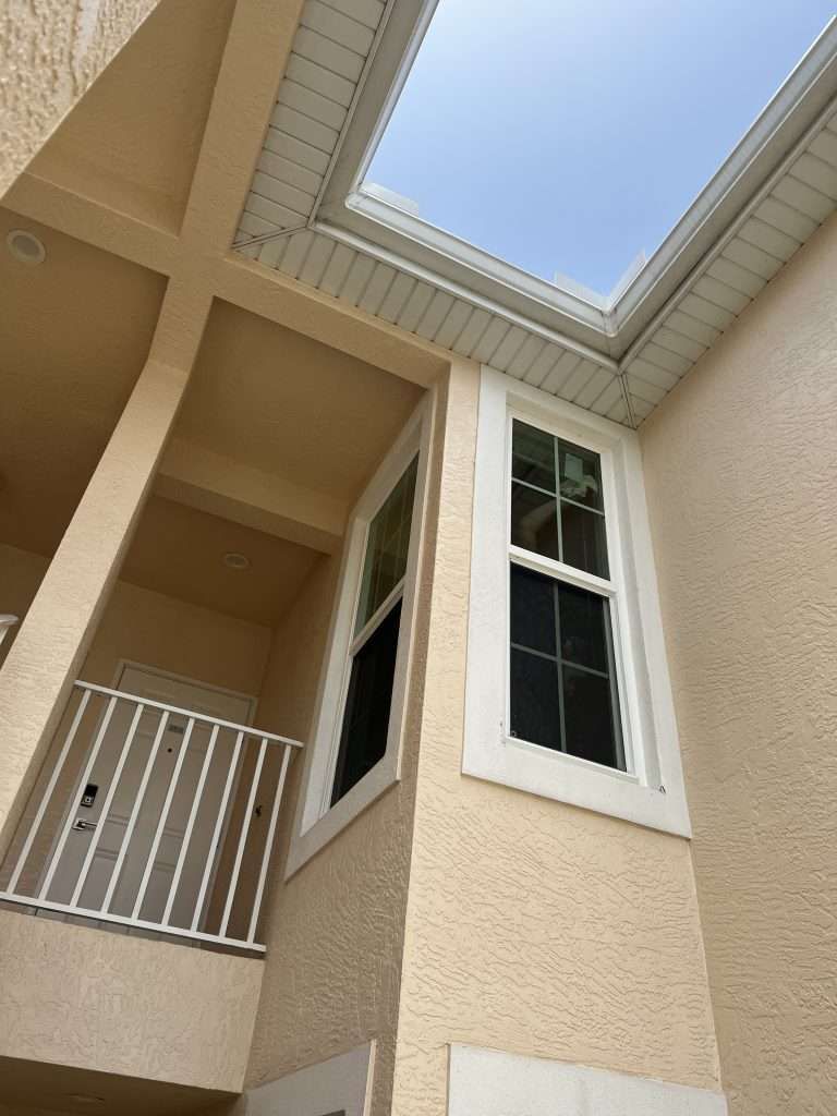 Looking Up at a House With a Balcony and a Skylight — Naples, FL — Wind Safe Shutters LLC