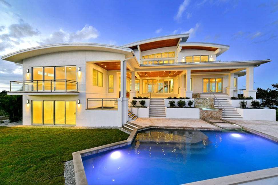 A Large House With a Swimming Pool in Front of It — Naples, FL — Wind Safe Shutters LLC