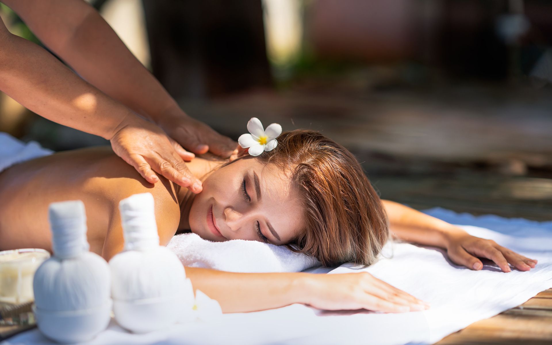 A woman is getting a massage at a spa with a flower in her hair.