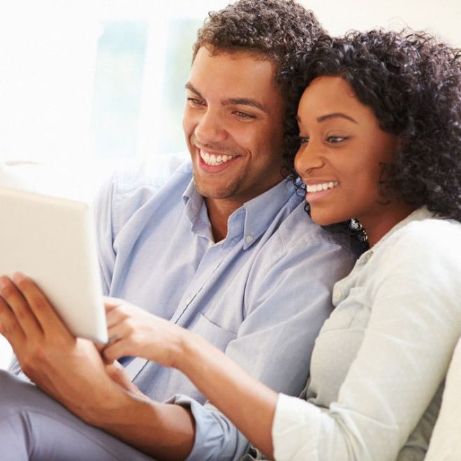 Couple Smiling While Looking at a Tablet