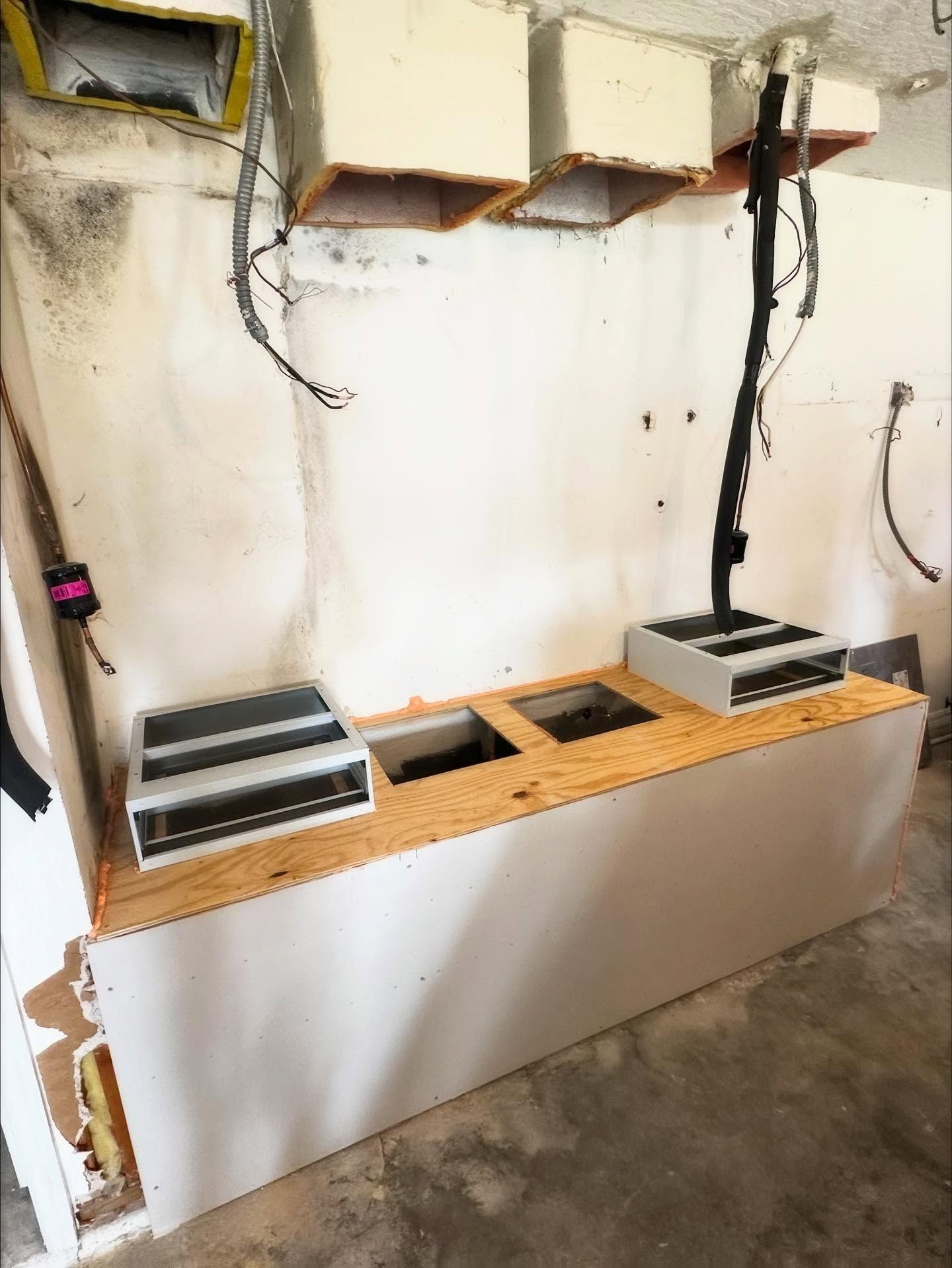 A partially constructed kitchen counter with installed appliances and overhead lighting; unfinished walls.
