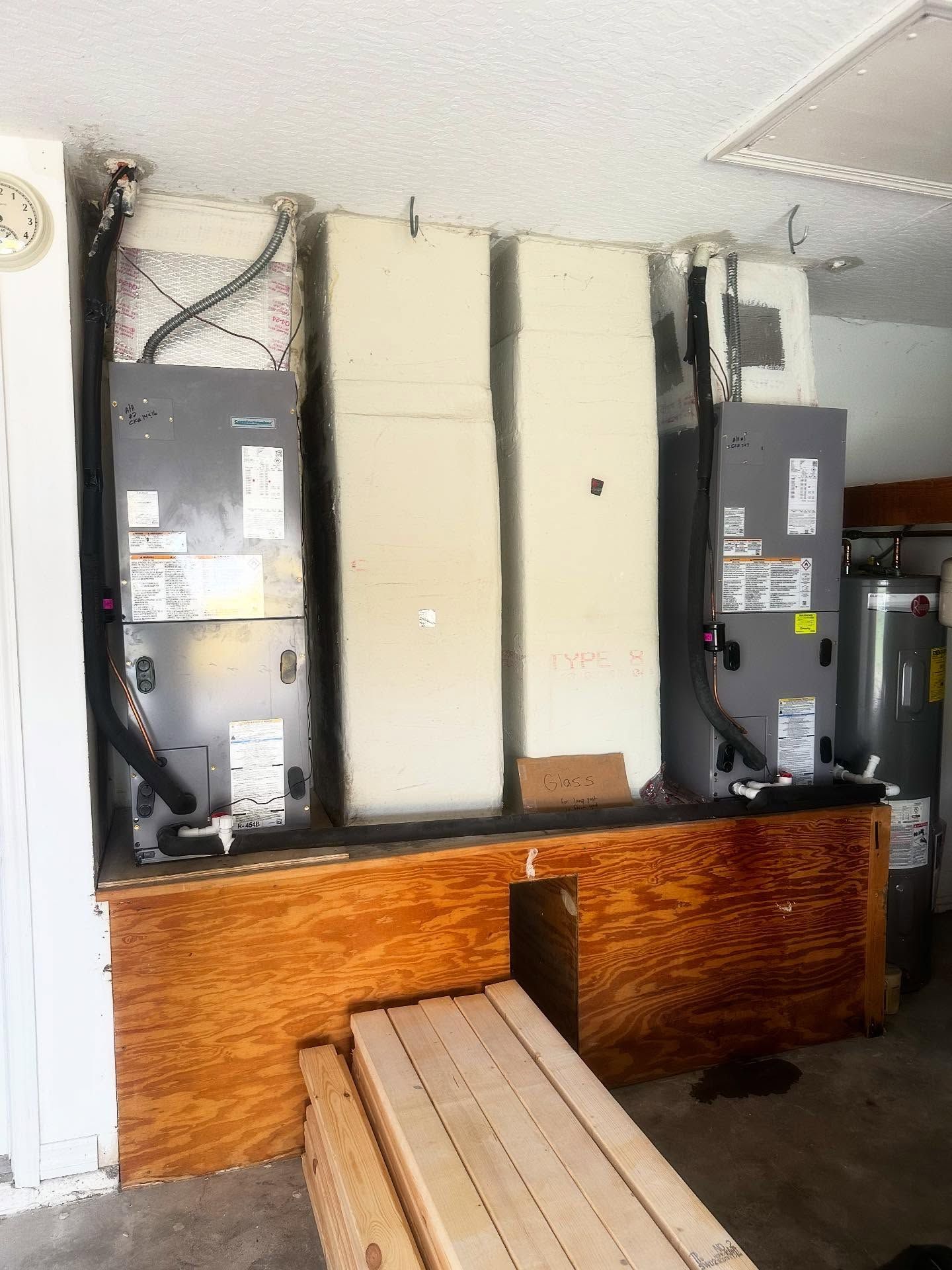HVAC units and water heater on a wooden platform in a garage setting.