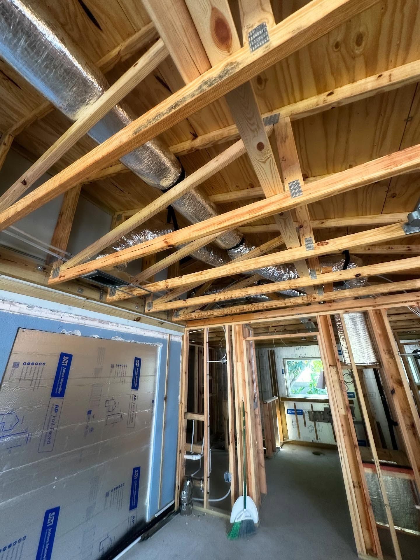 Wooden framework of a building's ceiling and walls under construction; ductwork is visible, room is unfinished.