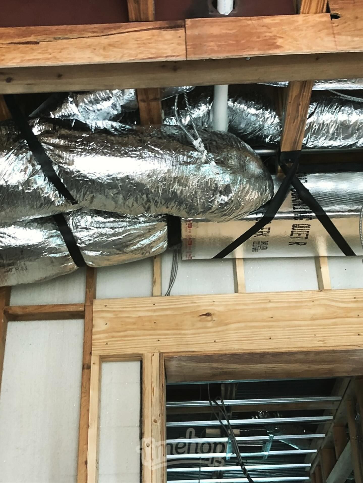 Construction showing ductwork, wooden framing, and insulation within a building.
