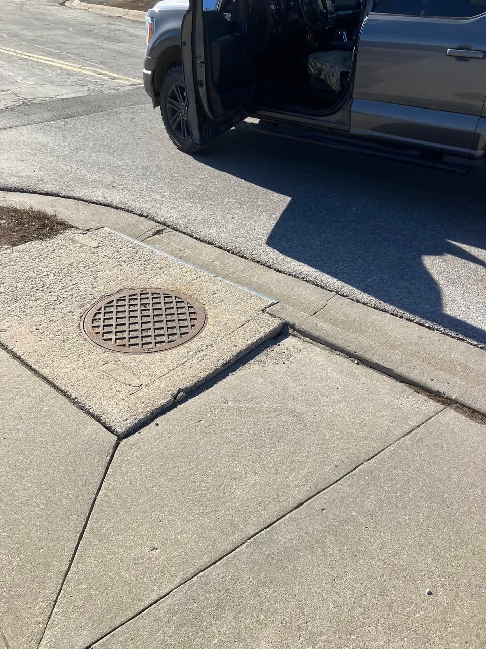 A car is parked on the side of the road with its door open.