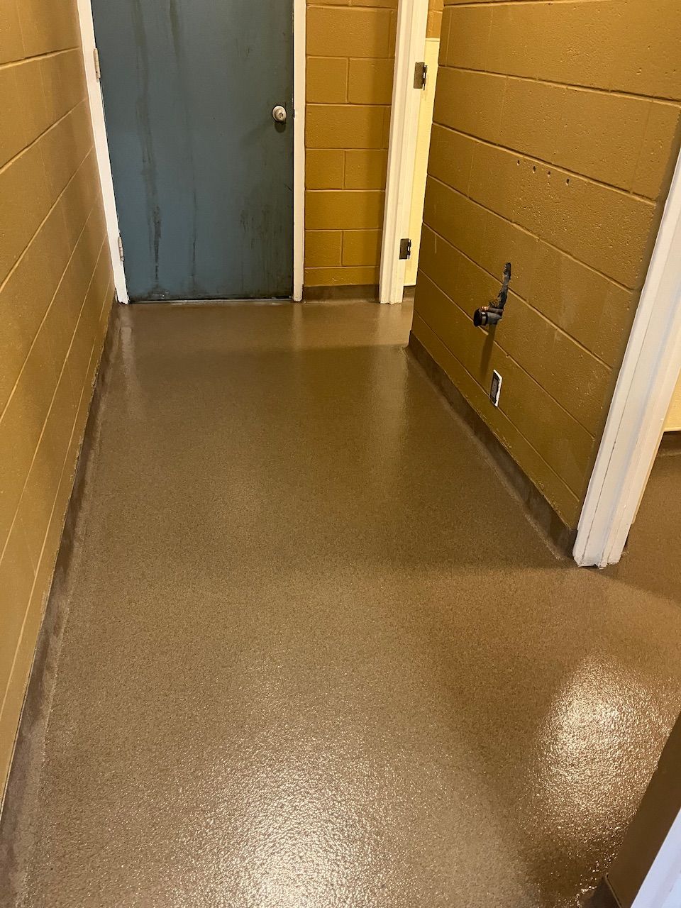 A hallway with a brown floor and a blue door.