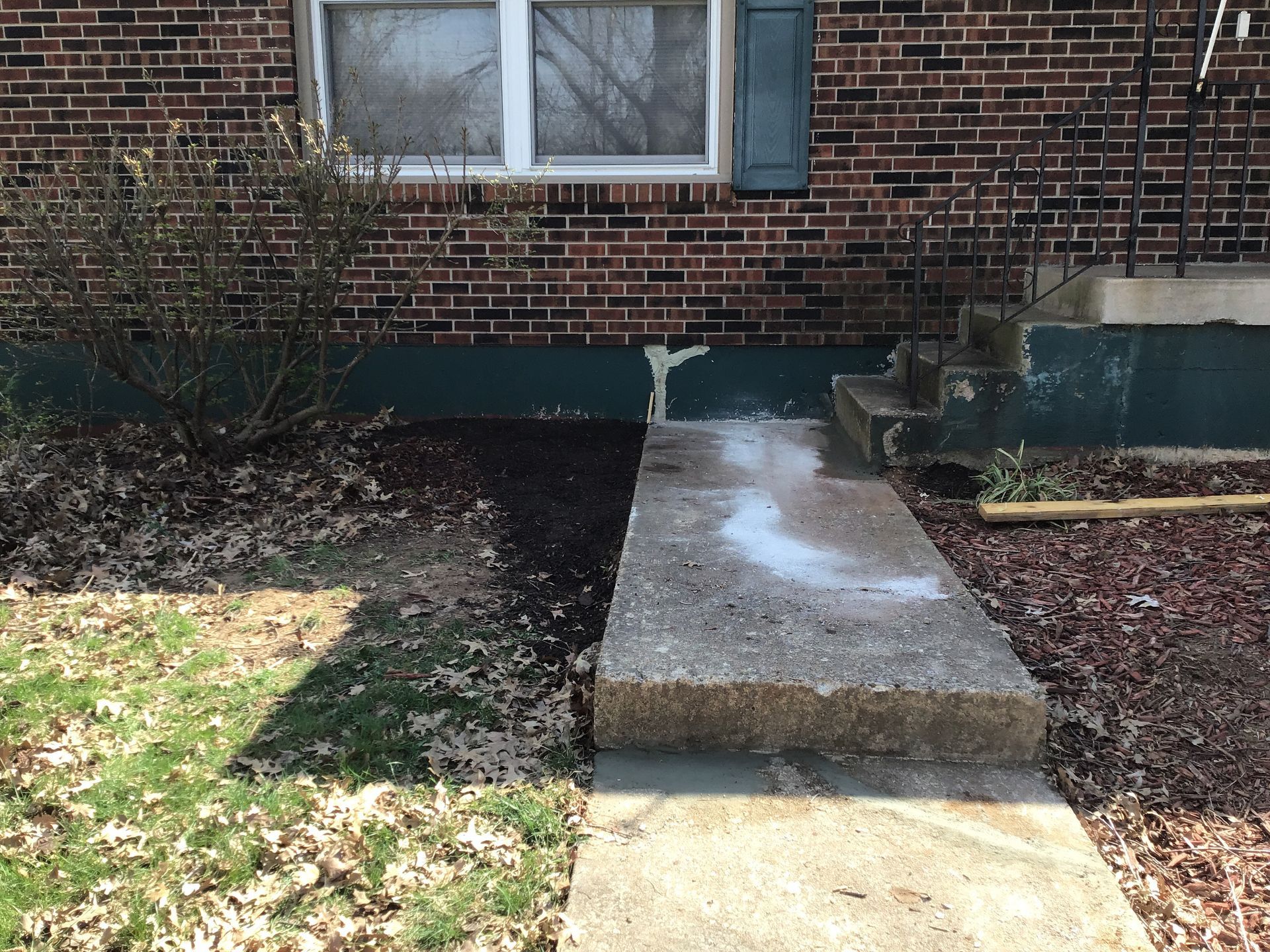 A brick house with a concrete walkway in front of it