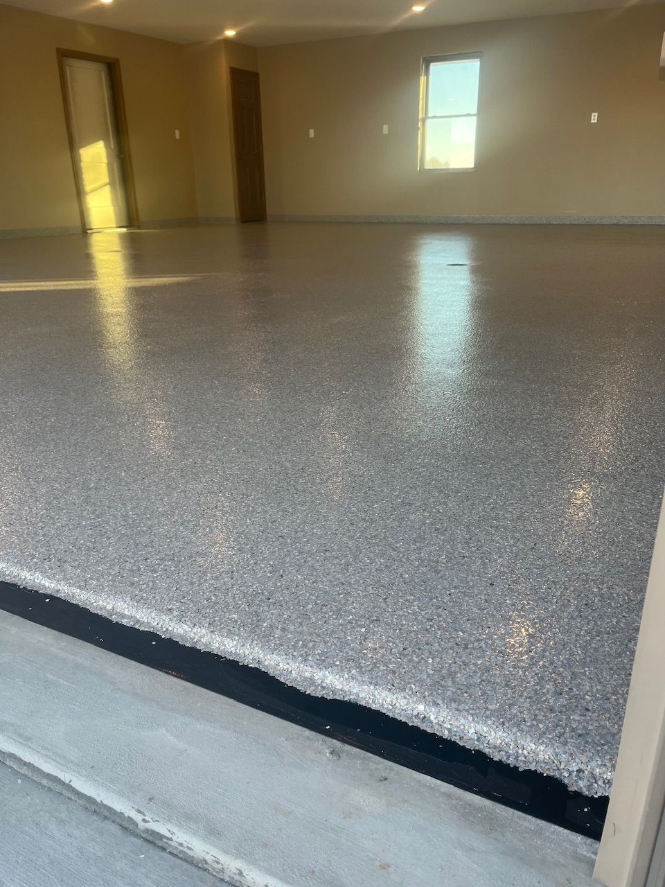 A garage with a shiny concrete floor and a window.