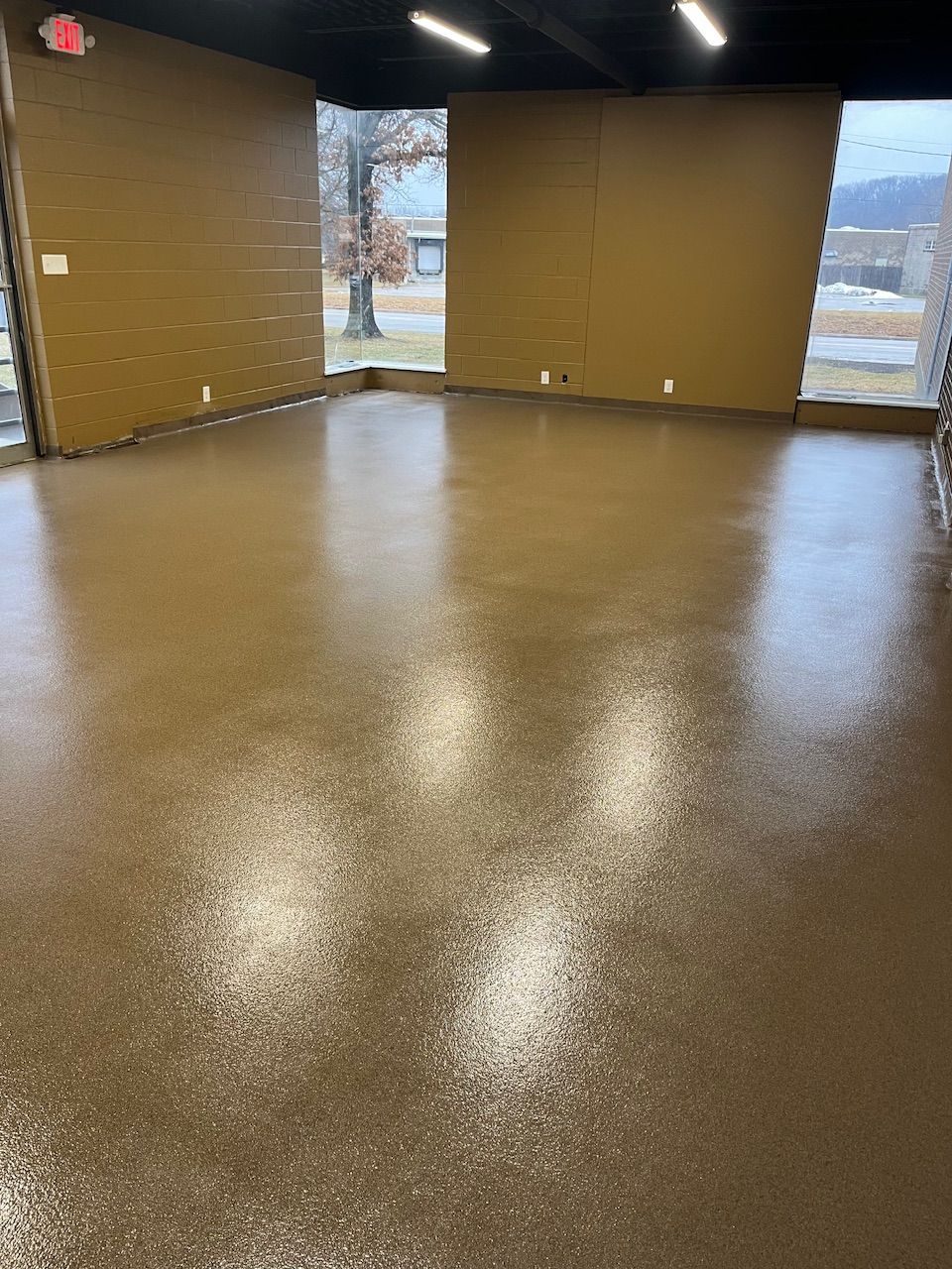 A large room with a brown floor and a window.
