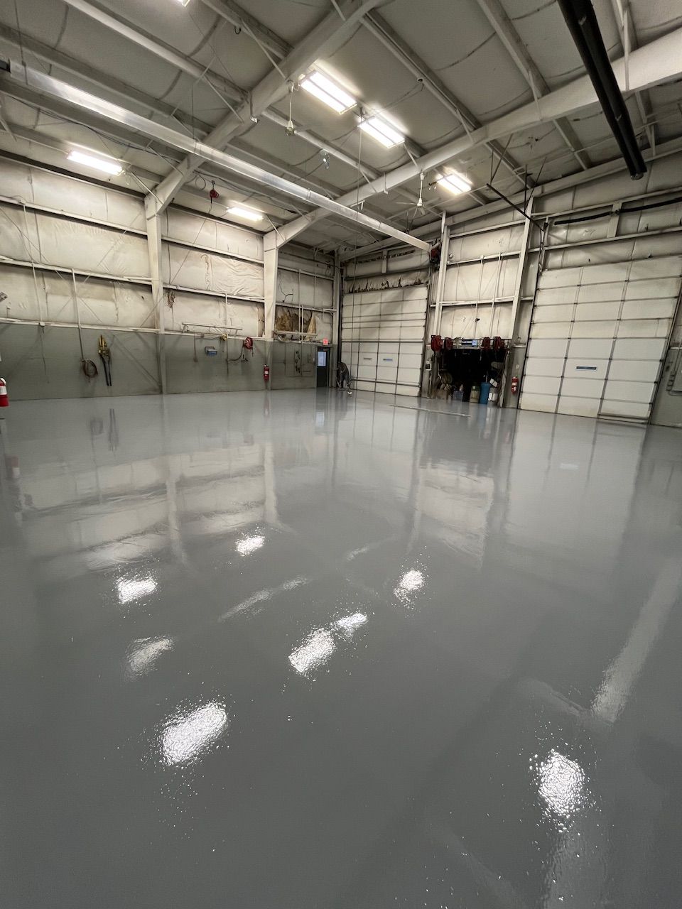 A large warehouse with a concrete floor and a garage door.
