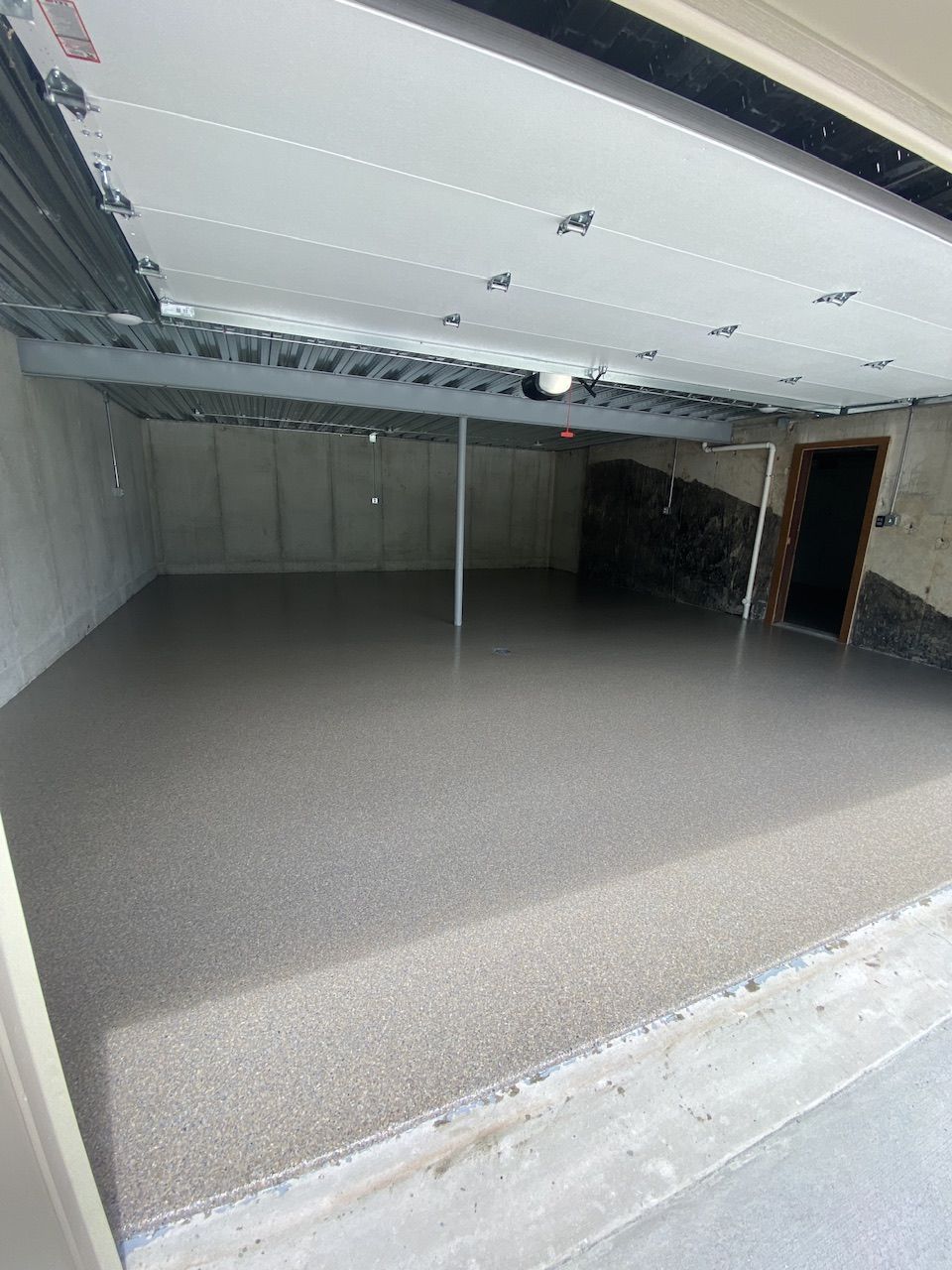 A garage with a garage door open and a concrete floor.