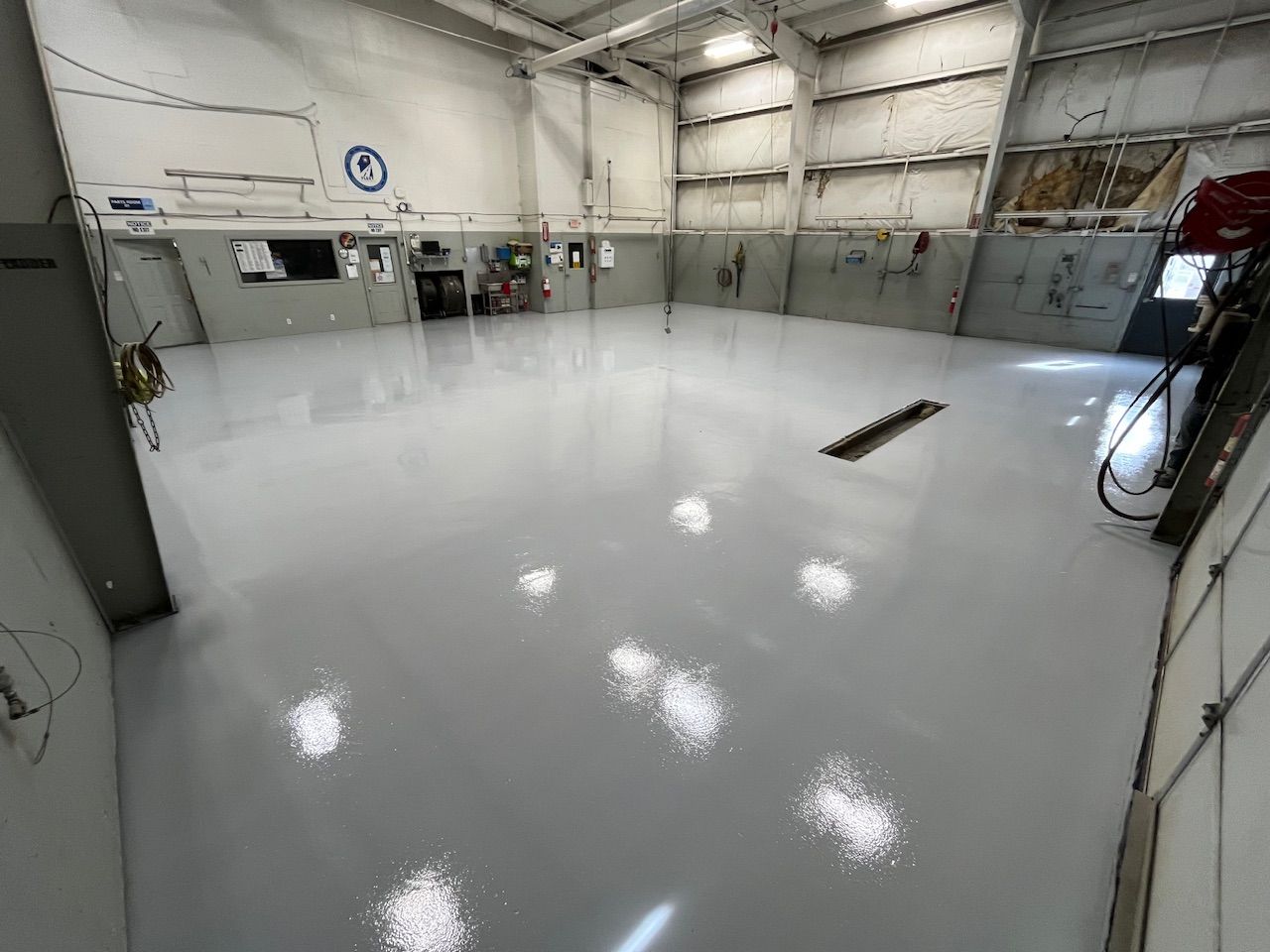 A large warehouse with a shiny white floor and a clock on the wall.