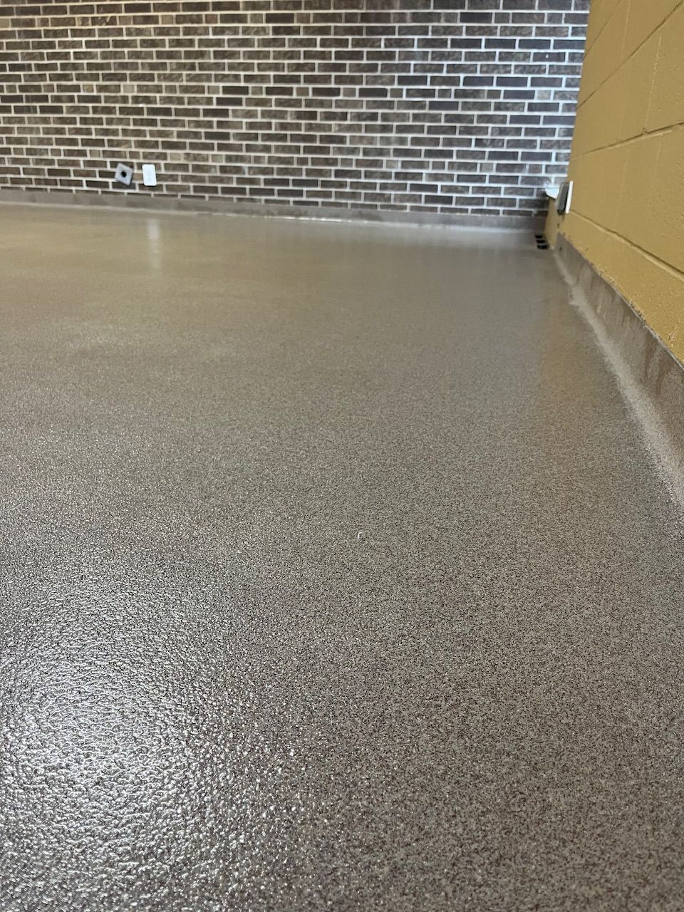 A close up of a garage floor with a brick wall in the background.
