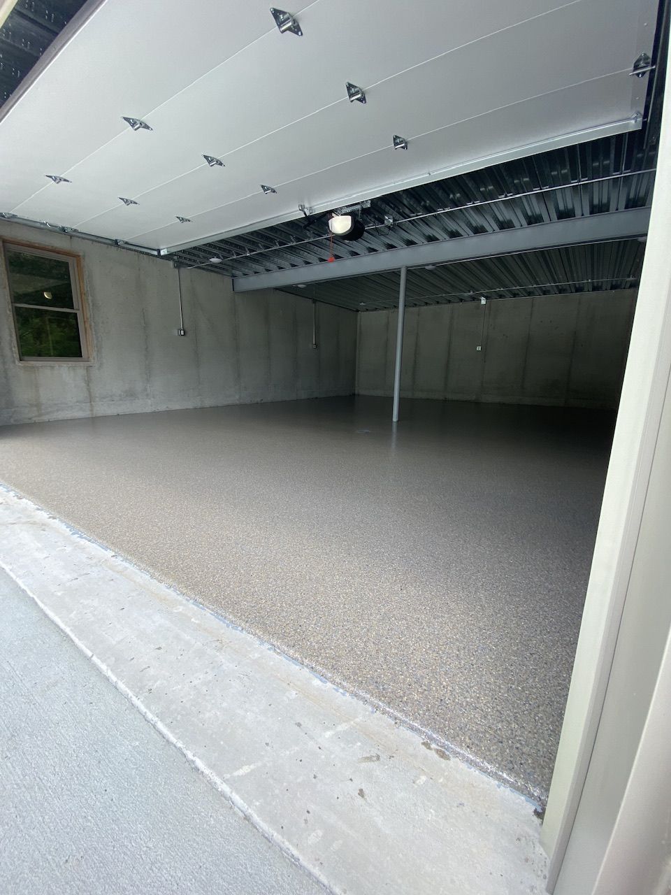 A garage with the door open and a concrete floor.