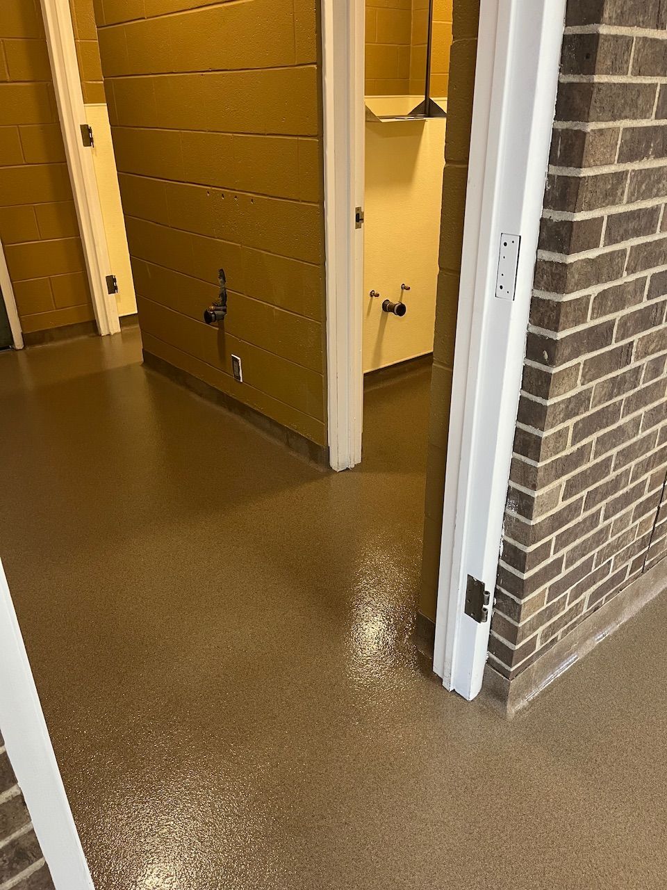 A bathroom with a brick wall and a concrete floor.