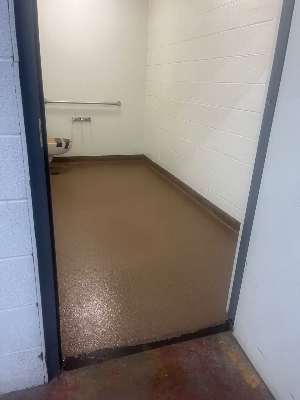 A bathroom with a brown floor and white walls.