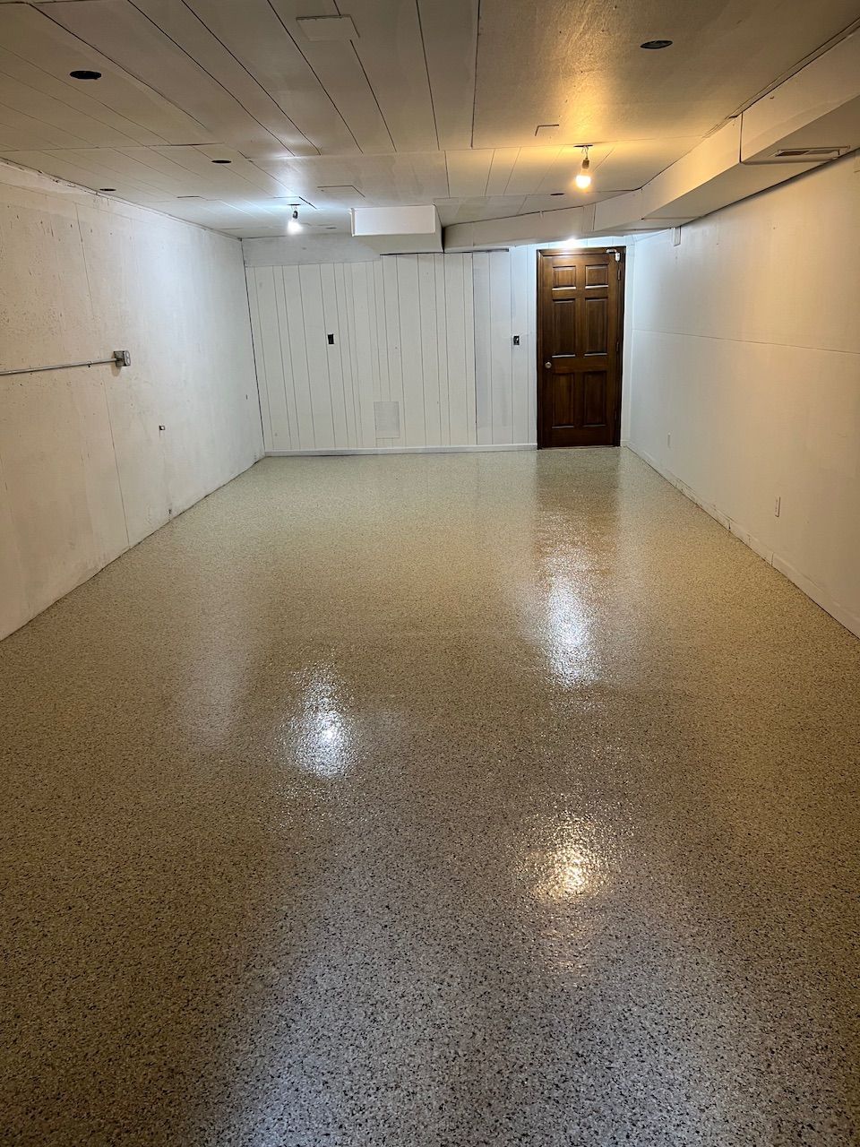 An empty basement with a door and a shiny floor.