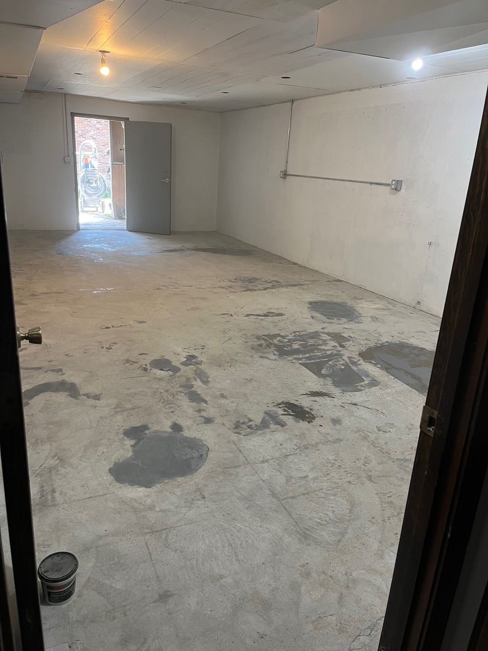 A large empty room with a concrete floor and a door.