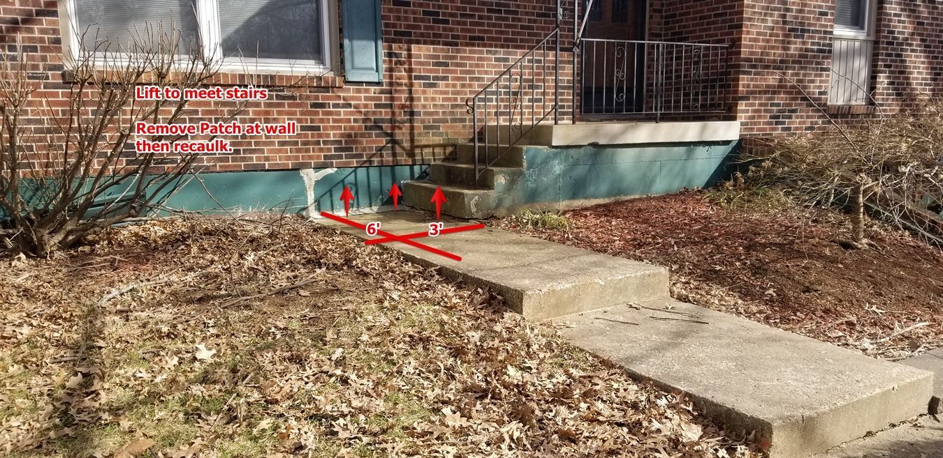 A brick house with a concrete walkway in front of it
