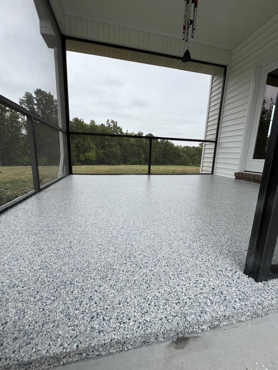 A porch with a screened in area and a concrete floor.