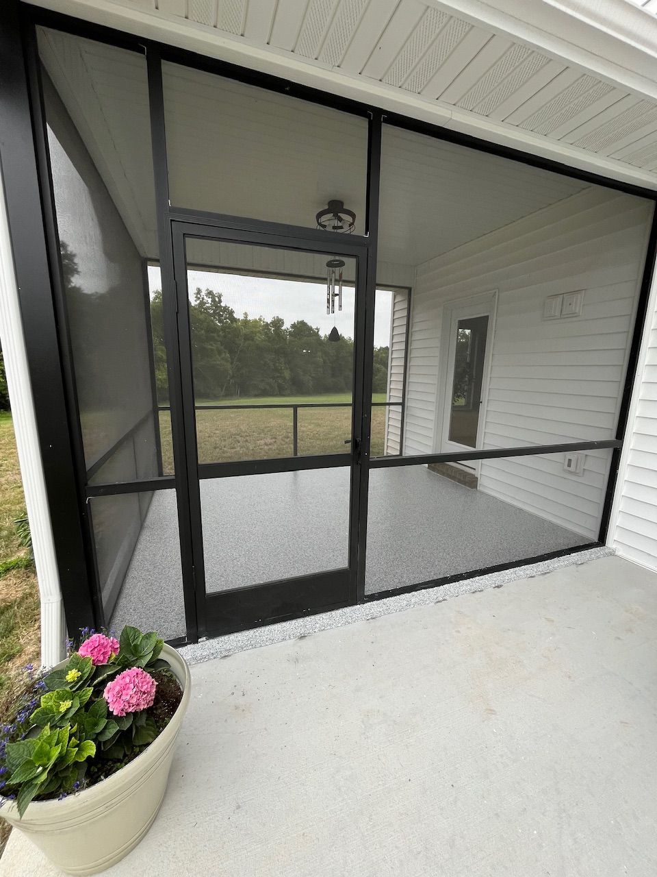A screened in porch with a potted plant in front of it