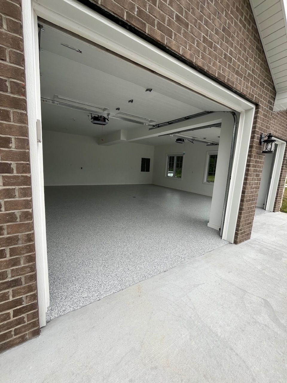 An empty garage with a brick wall and a concrete floor.