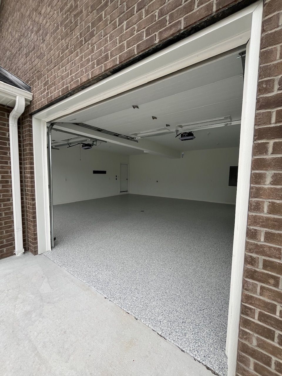 An empty garage with a brick wall and a concrete floor.