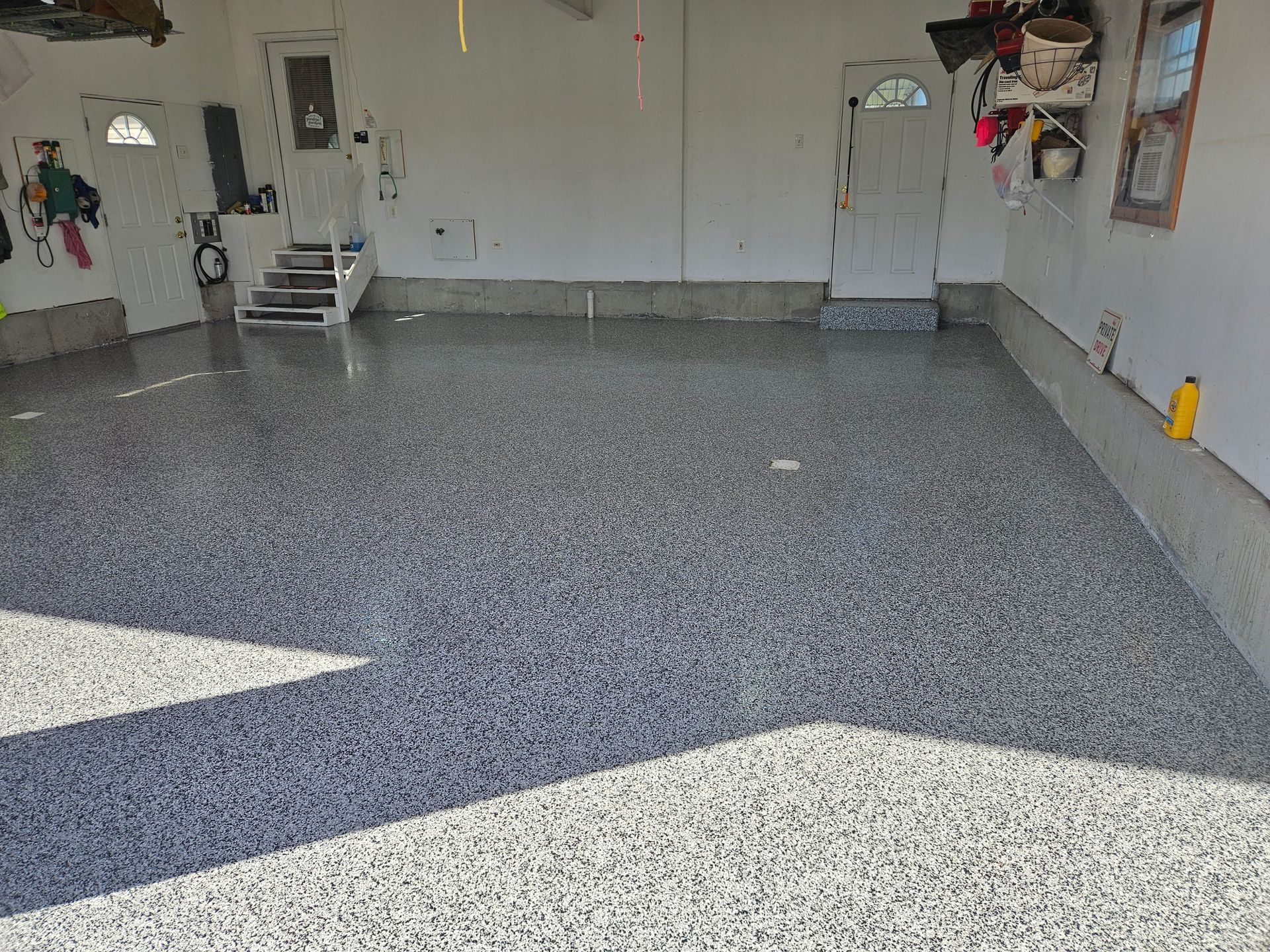 A garage with a gray and white floor and a door.