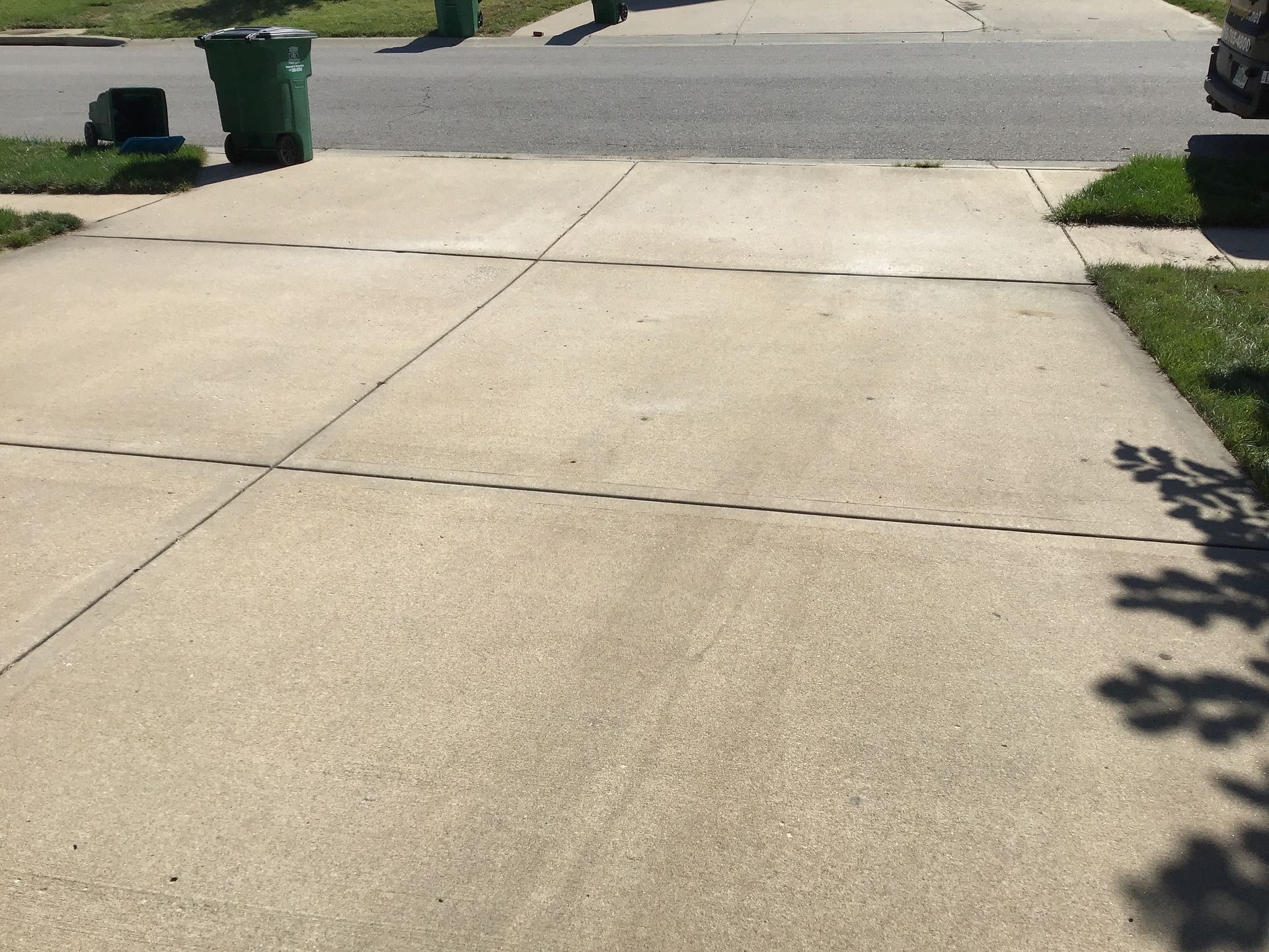 A sidewalk with a green trash can on it
