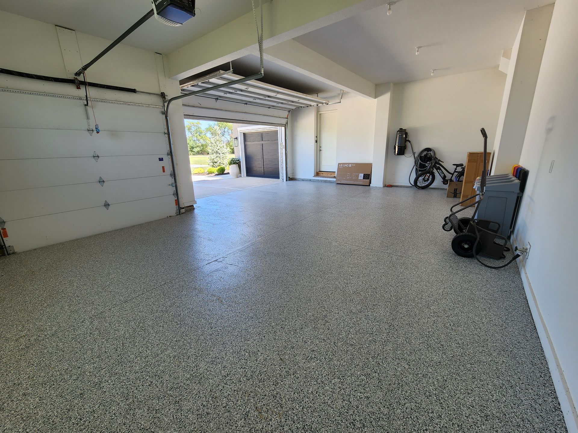 A large empty garage with a garage door open and a concrete floor.
