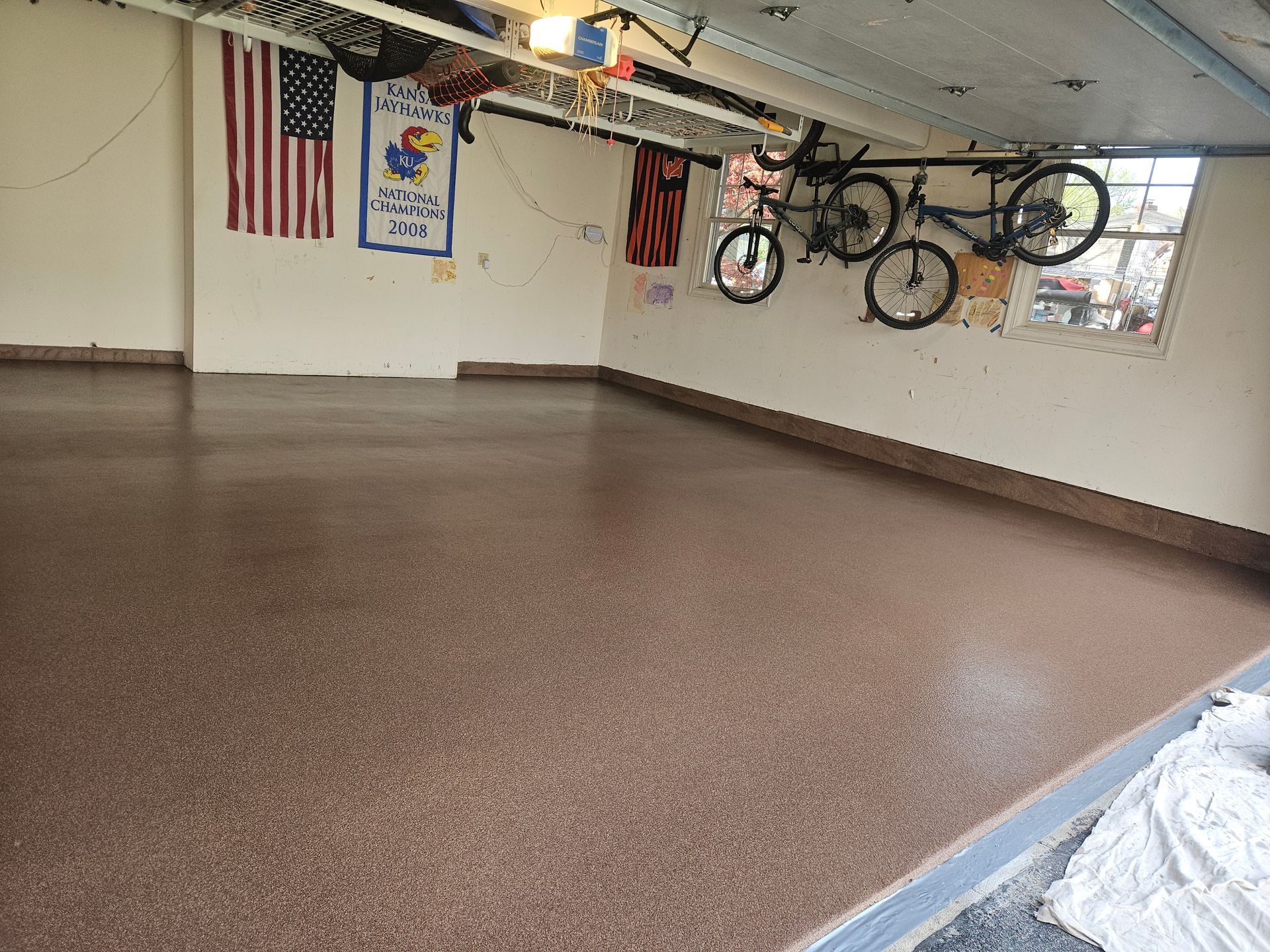 Two bikes are hanging from the ceiling of a garage.