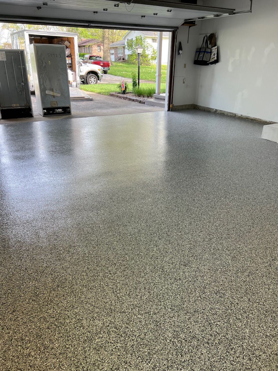 A garage with a concrete floor and a garage door open.