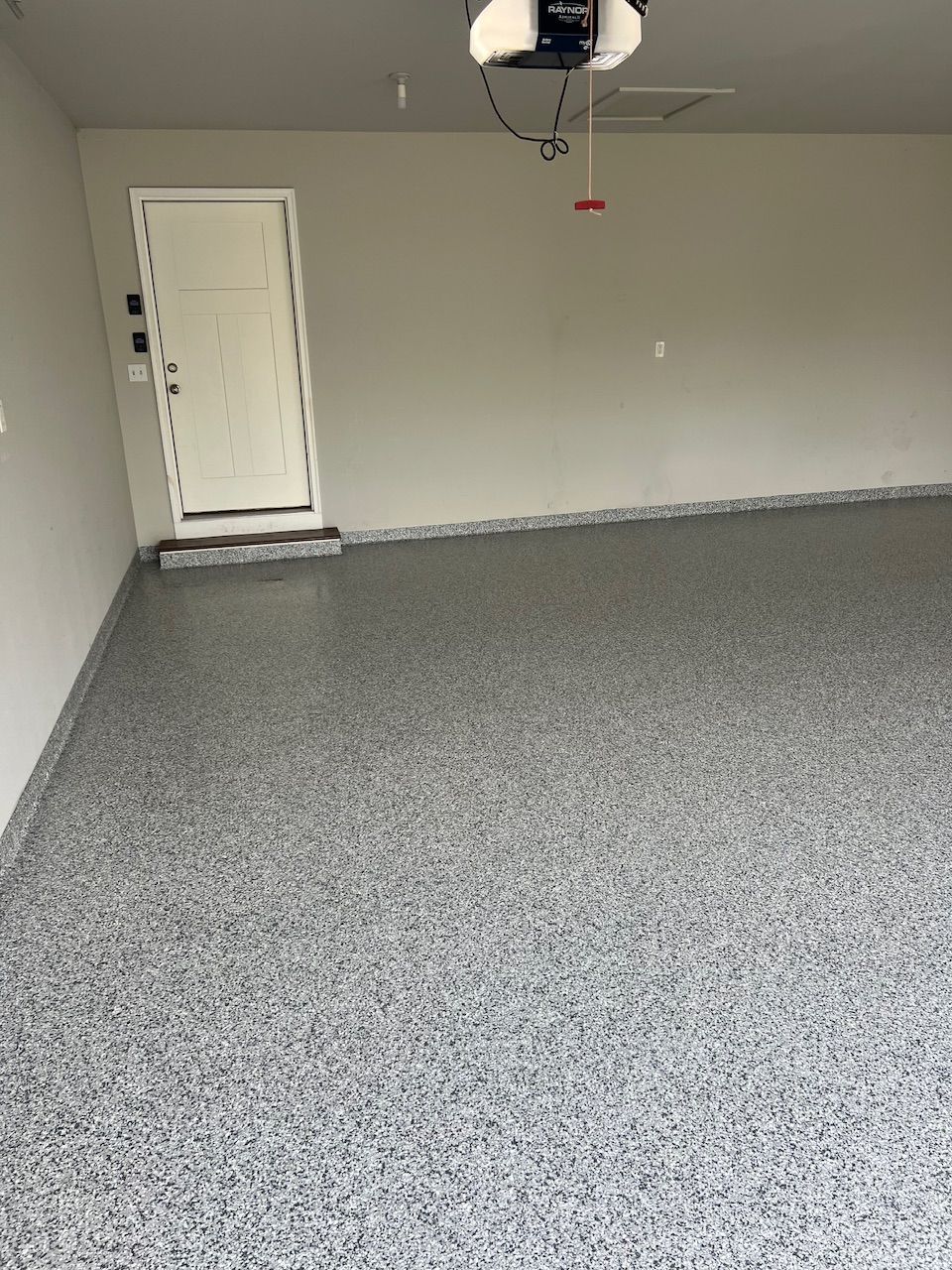 A garage with a garage door open and a gray floor.