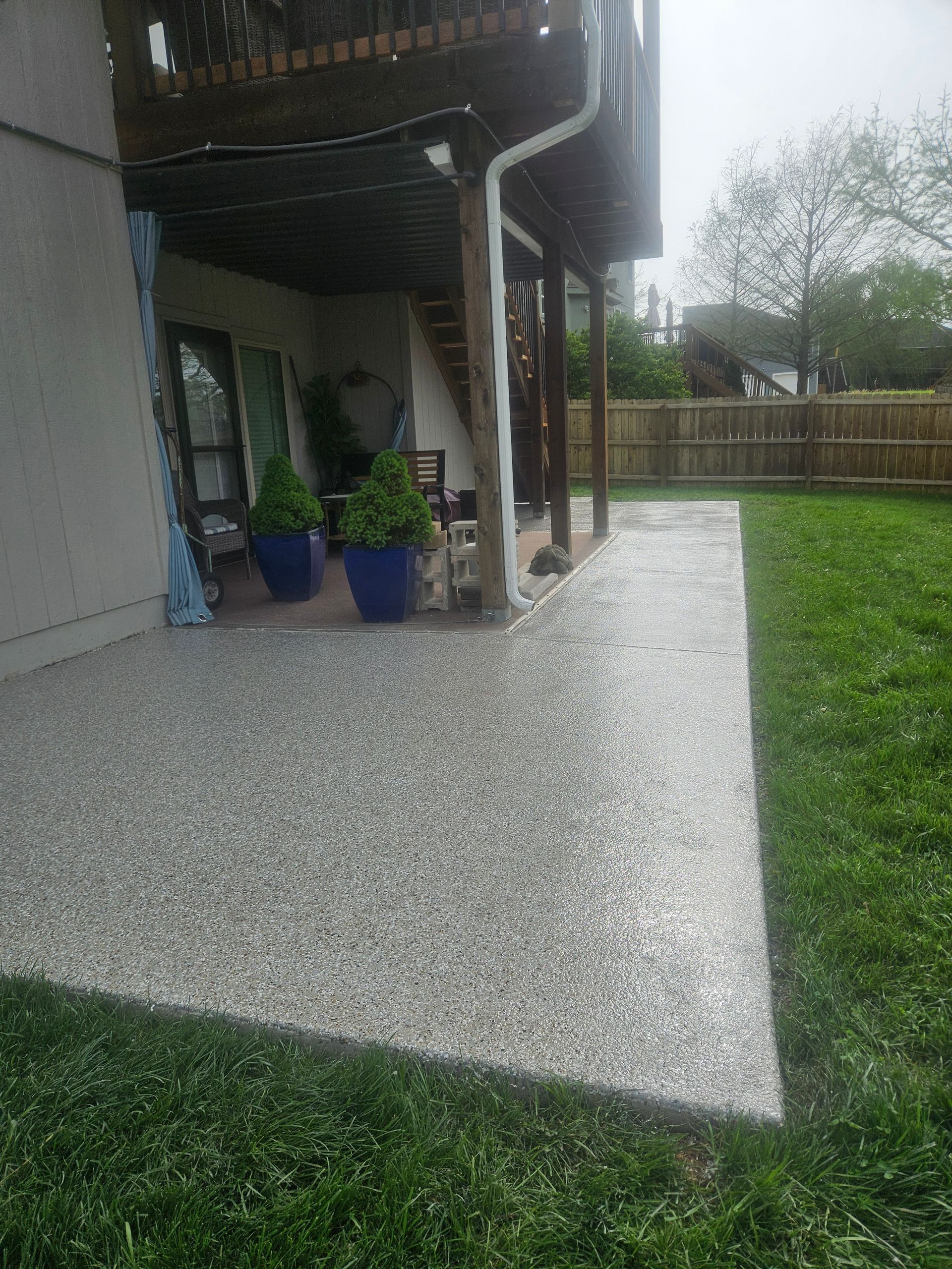 A patio with potted plants and a deck in the backyard of a house.