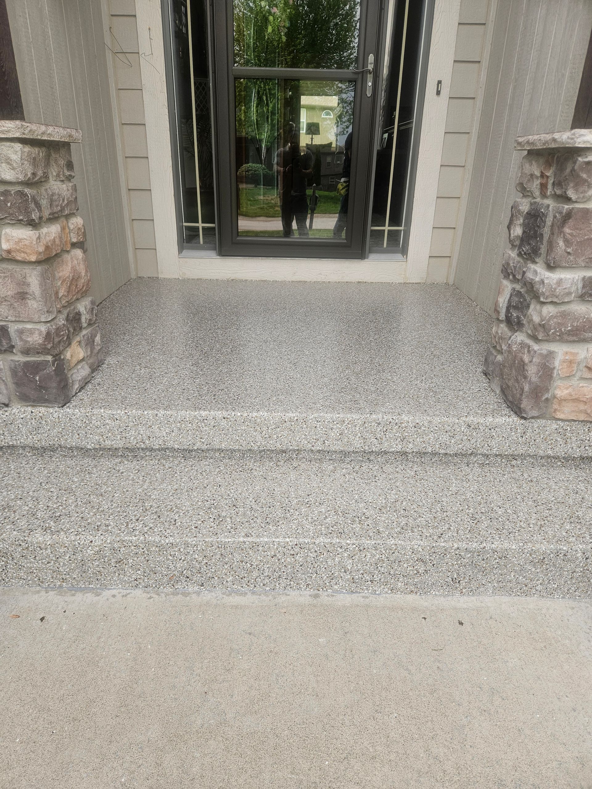 A person is standing in front of a house with a door and steps.